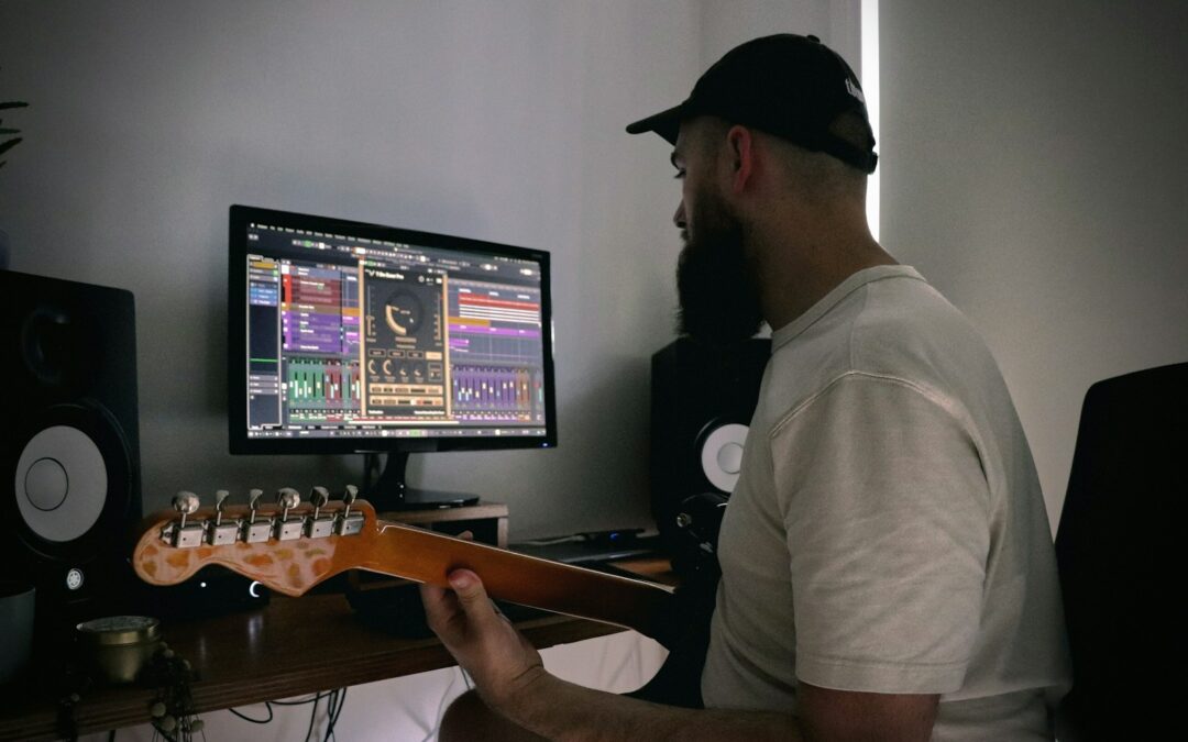 a man sitting in front of a computer playing a guitar